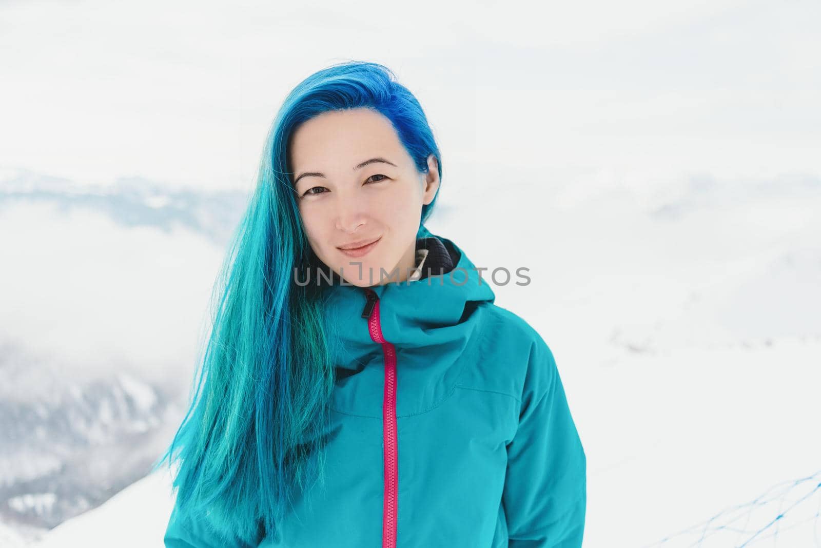 Beautiful smiling young woman resting on ski resort in winter outdoor, looking at camera