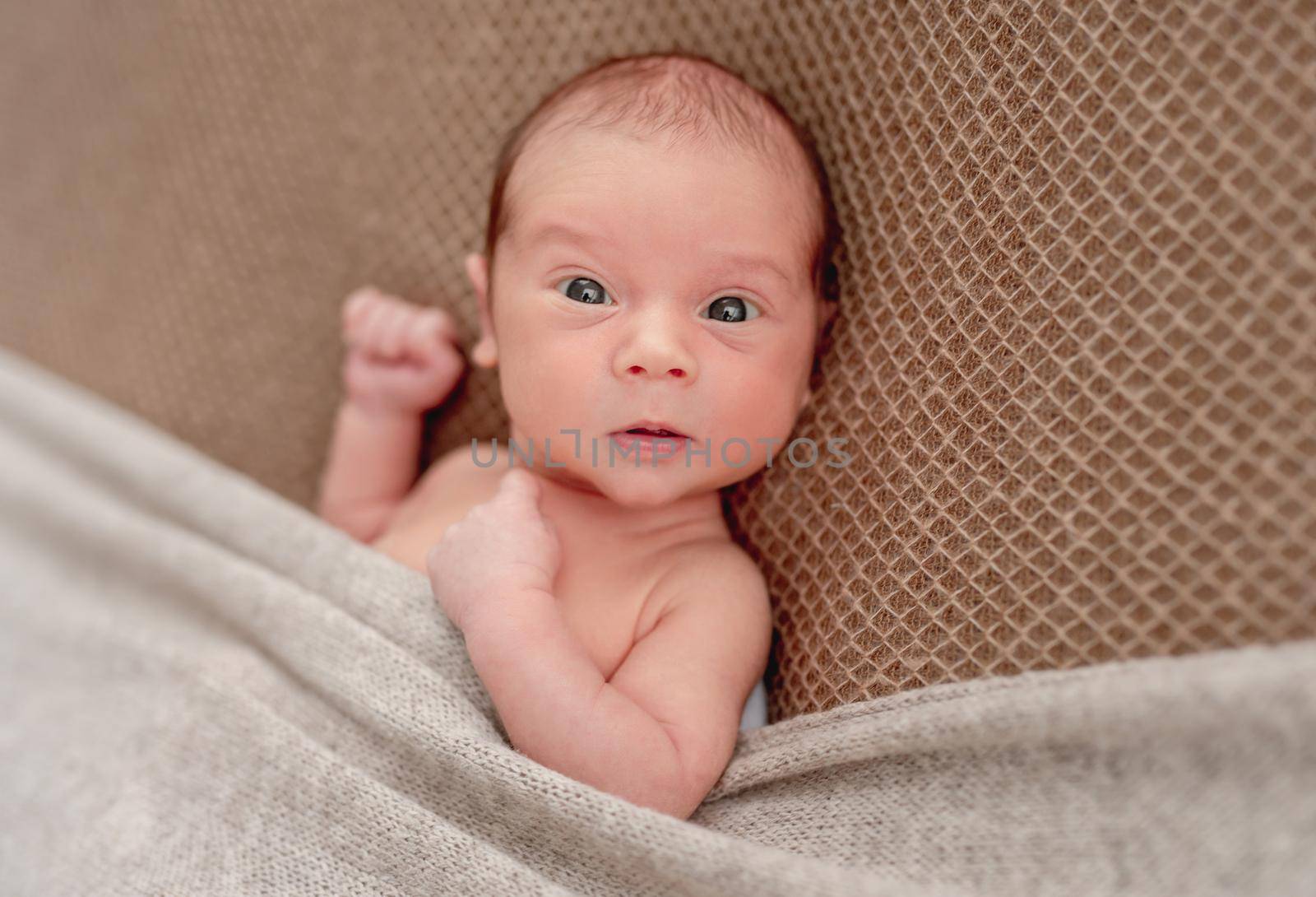 Cute sleepless newborn in funny hat looking to side