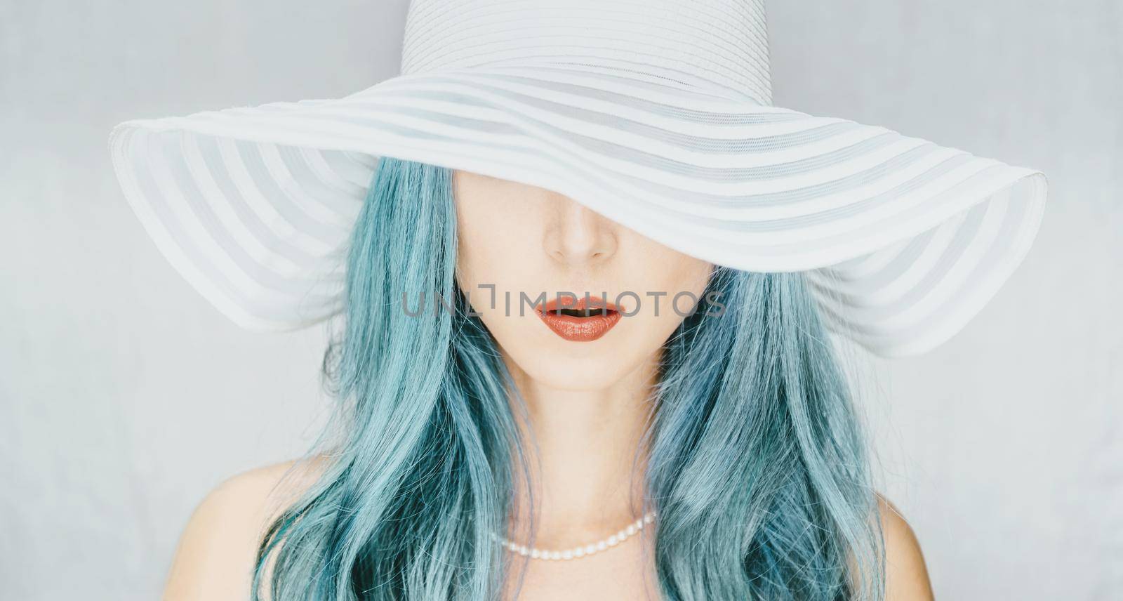 Young woman with blue hair in a hat with wide brim, fashion and beauty.