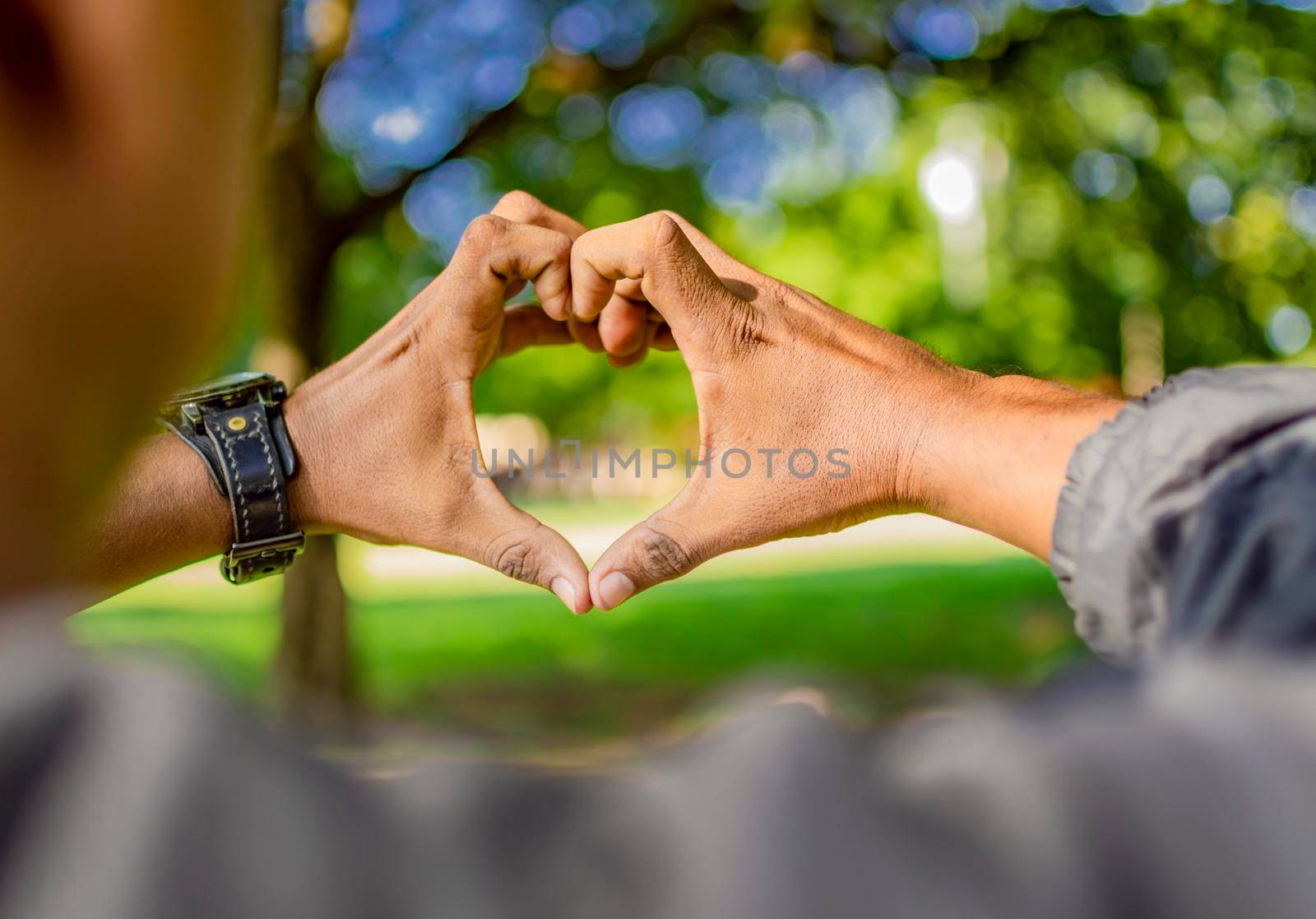 Close up of two hands together in a heart shape, hands together in a heart shape, young man putting fingers together in a heart shape by isaiphoto