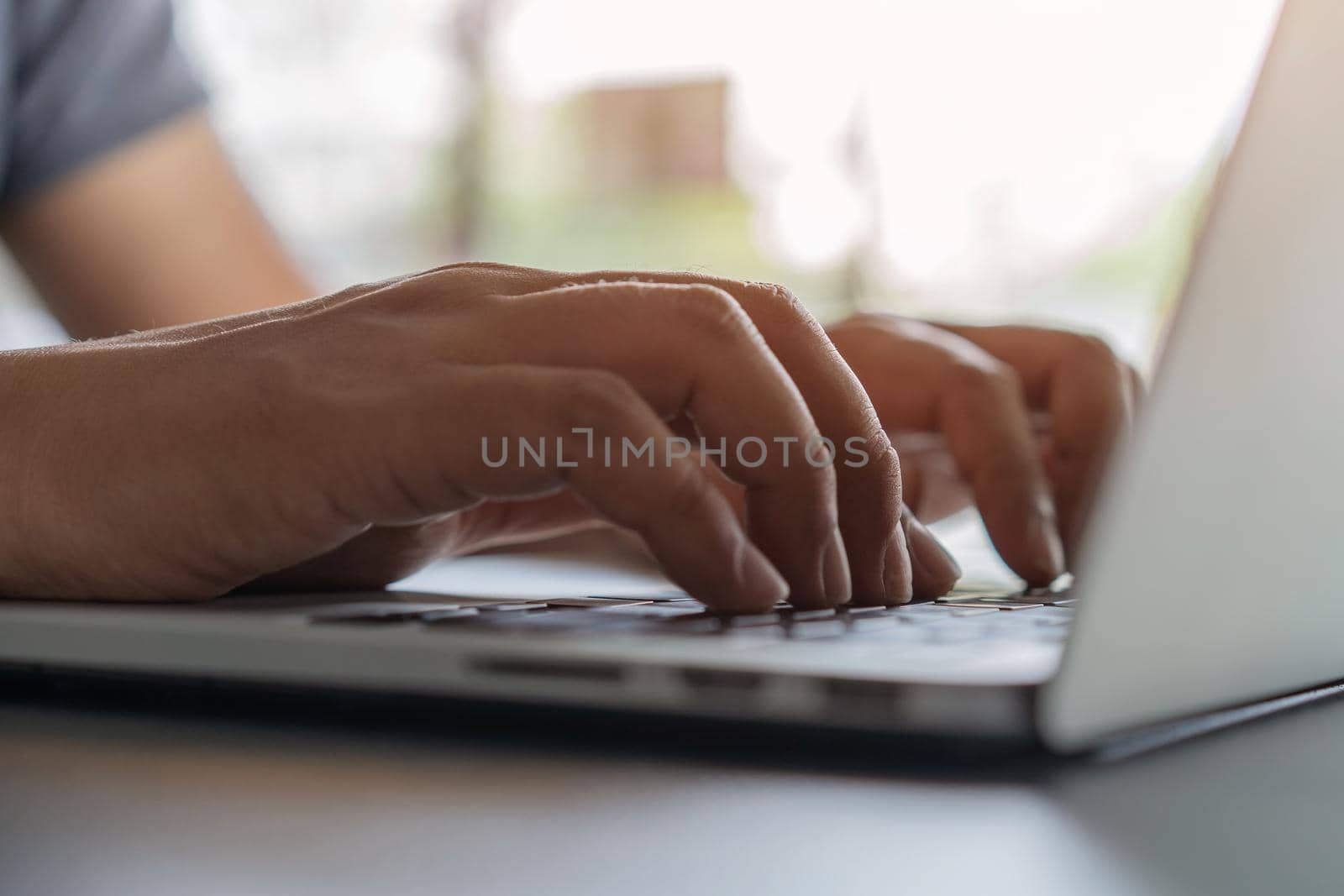 Closeup of hands working and typing on laptop keyboard on table 