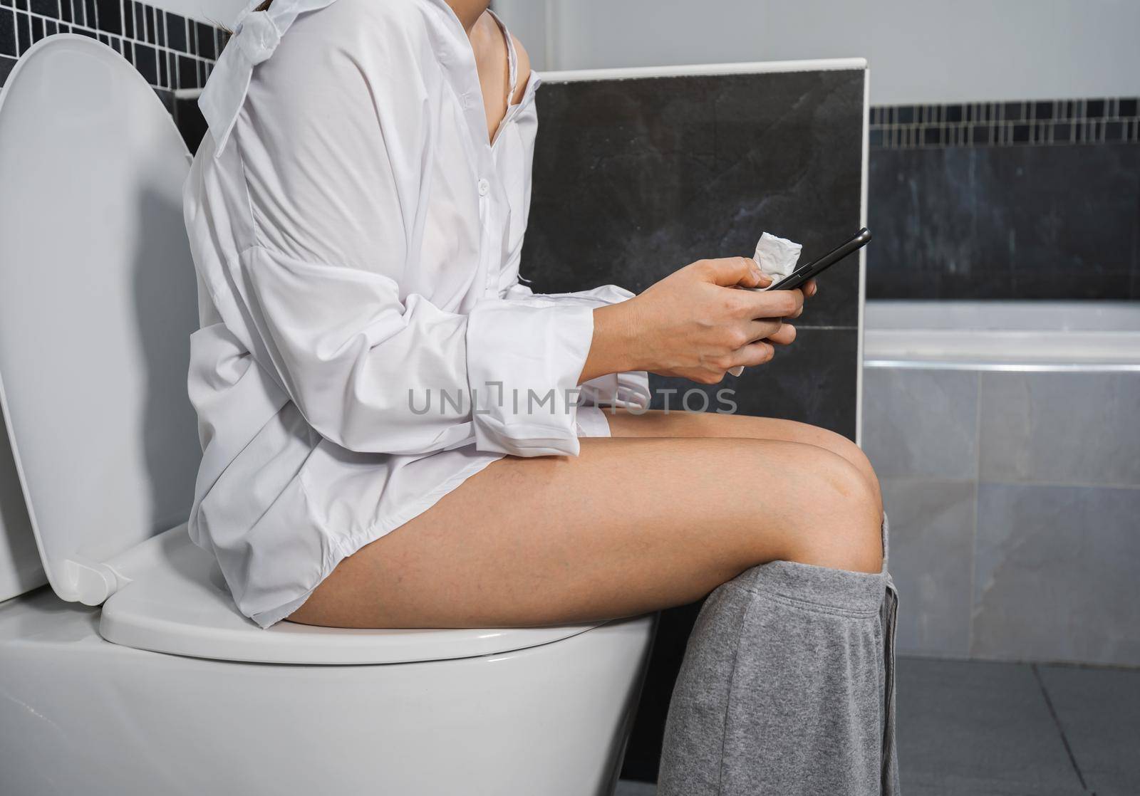 woman using mobile phone and sitting on the toilet 
