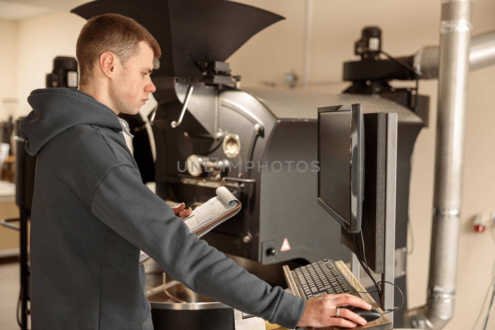 Young specialist worker is roasting coffee in hangar