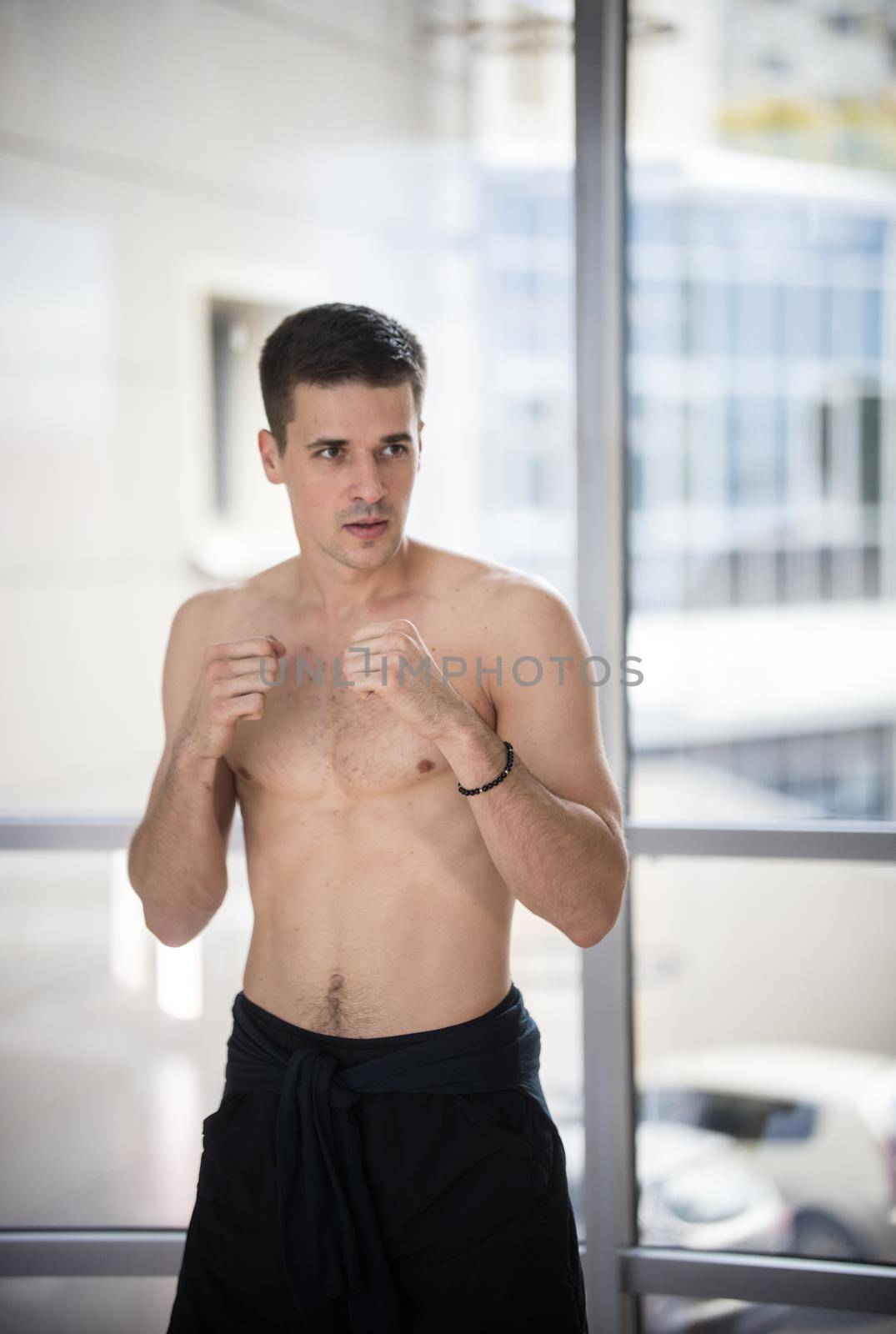 An athletic man standing in fighting pose in the studio. Mid shot