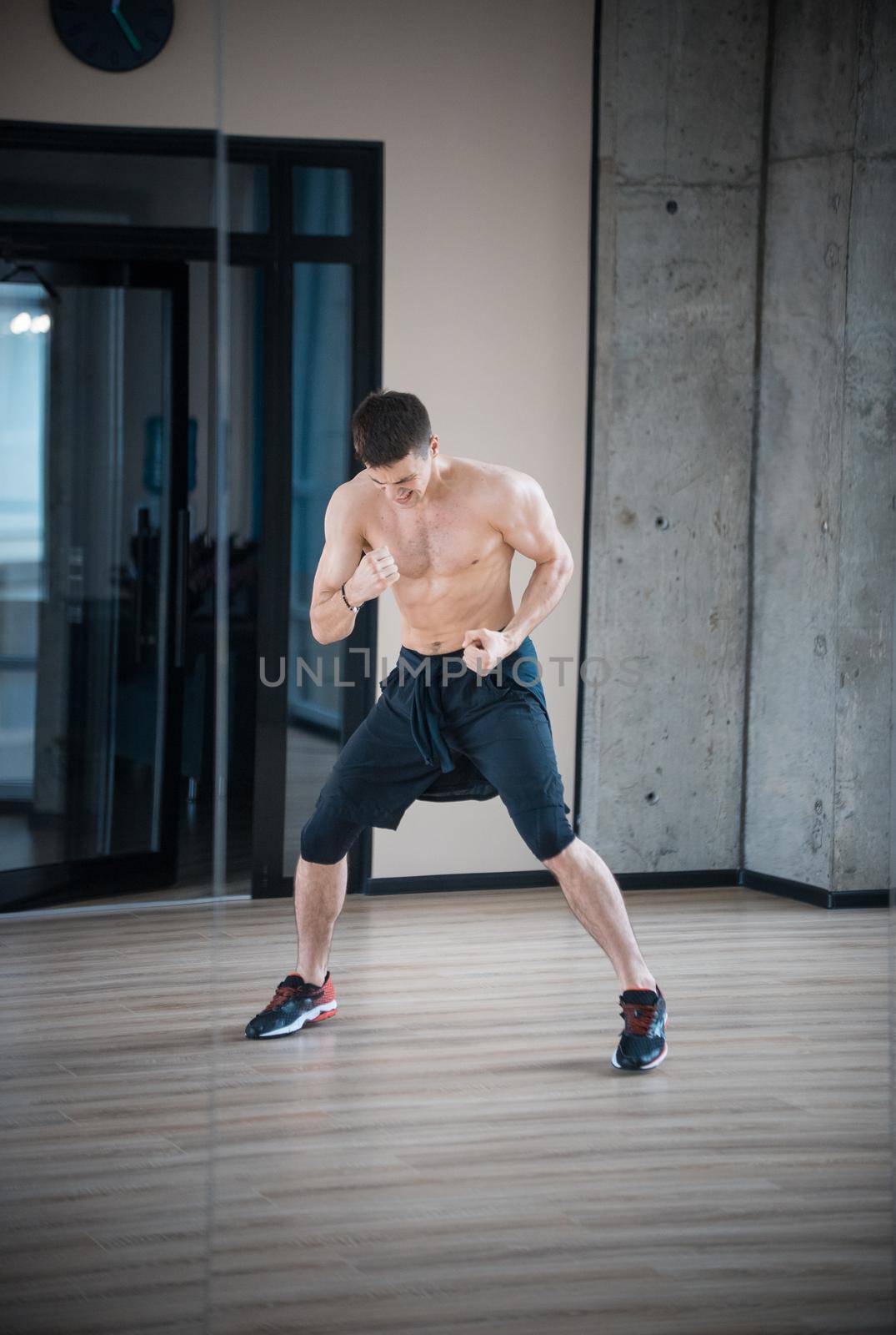 An athletic half naked man boxer training in the studio. Mid shot