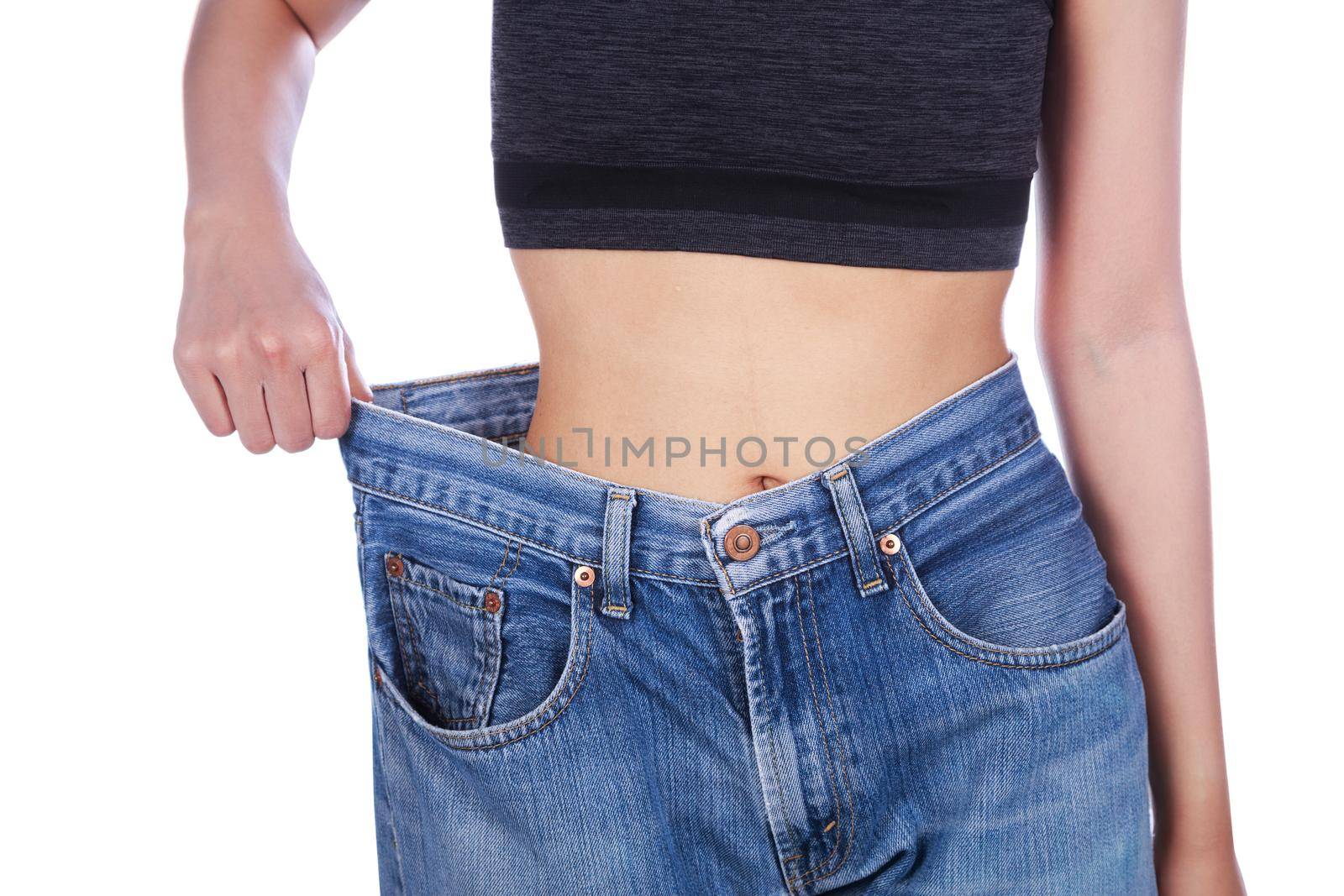 close up of woman show her weight loss and wearing her old jeans isolated on white background by geargodz