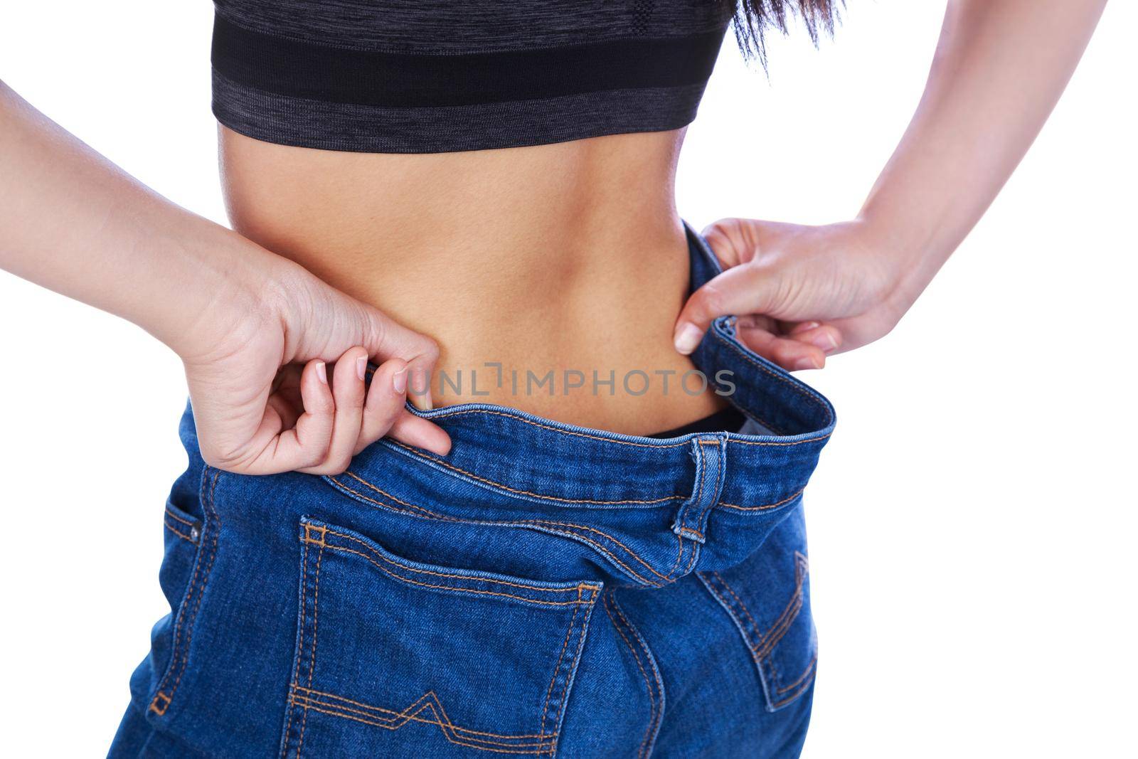 close up of woman show her weight loss and wearing her old jeans isolated on white background by geargodz