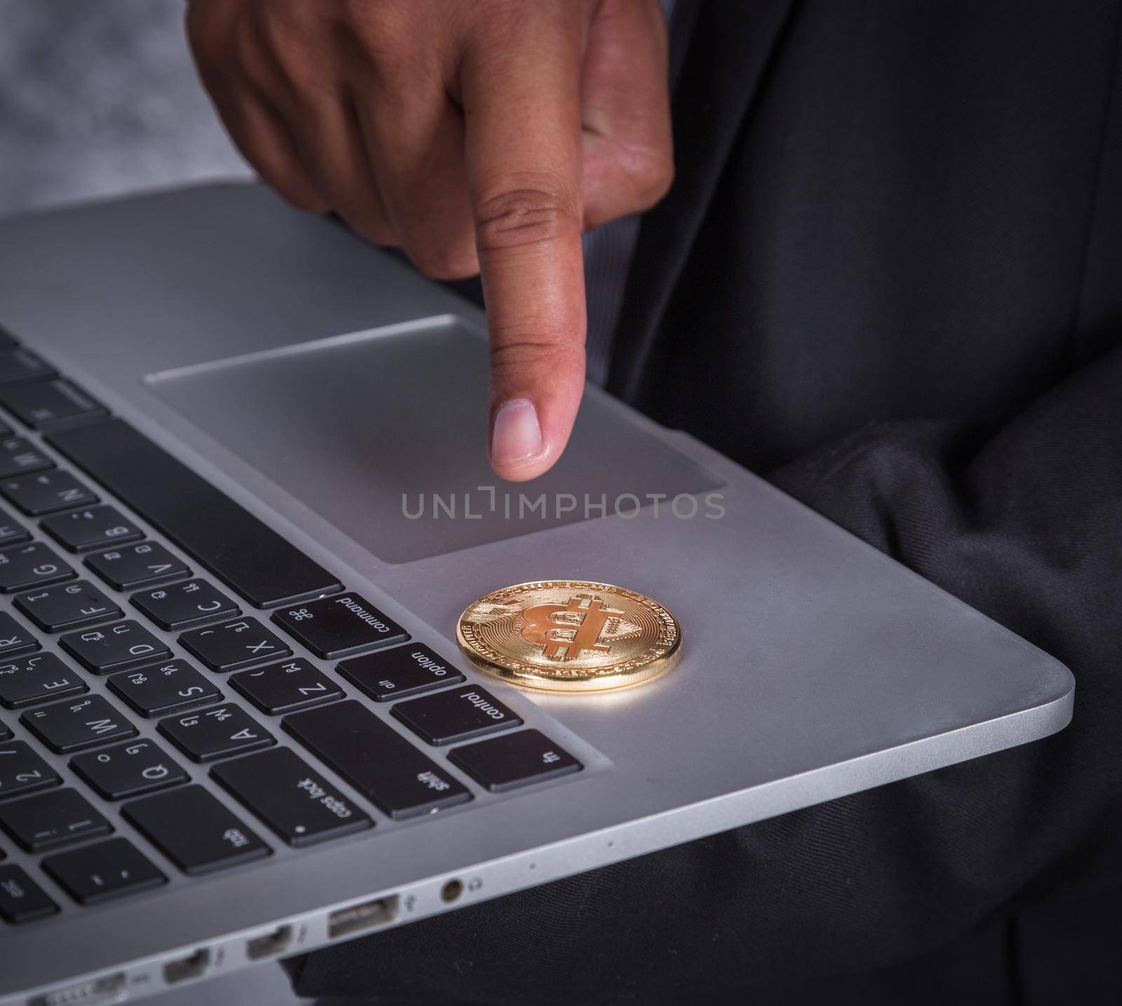 hand pointing golden bitcoin with laptop computer  by geargodz