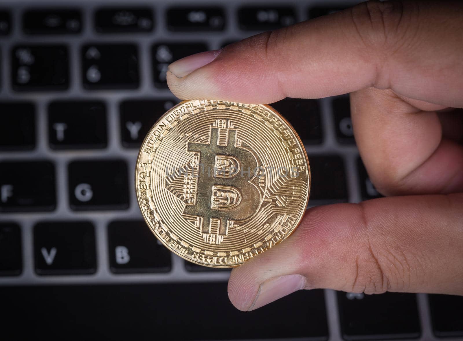 hand holding golden bitcoin with laptop computer  by geargodz