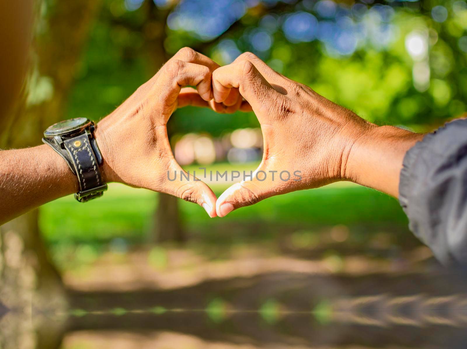 Close up of two hands together in a heart shape, hands together in a heart shape, young man putting fingers together in a heart shape by isaiphoto