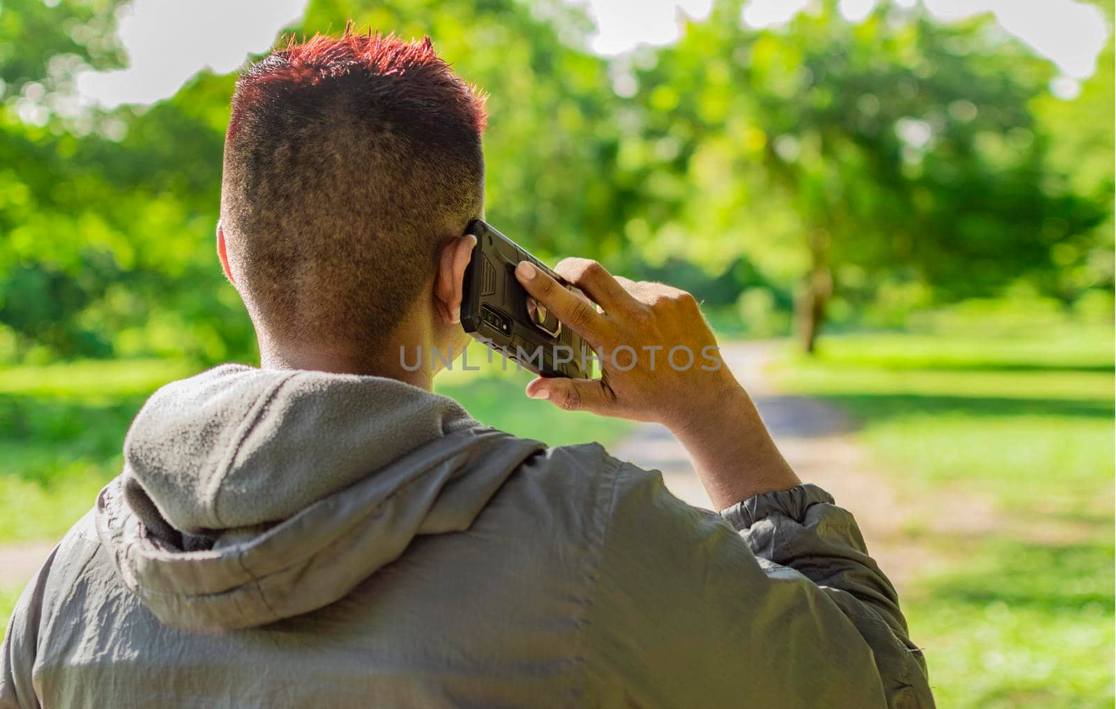 Close up of a man calling on the phone, close up of a young man calling on the phone in the field, man from back calling on cell phone