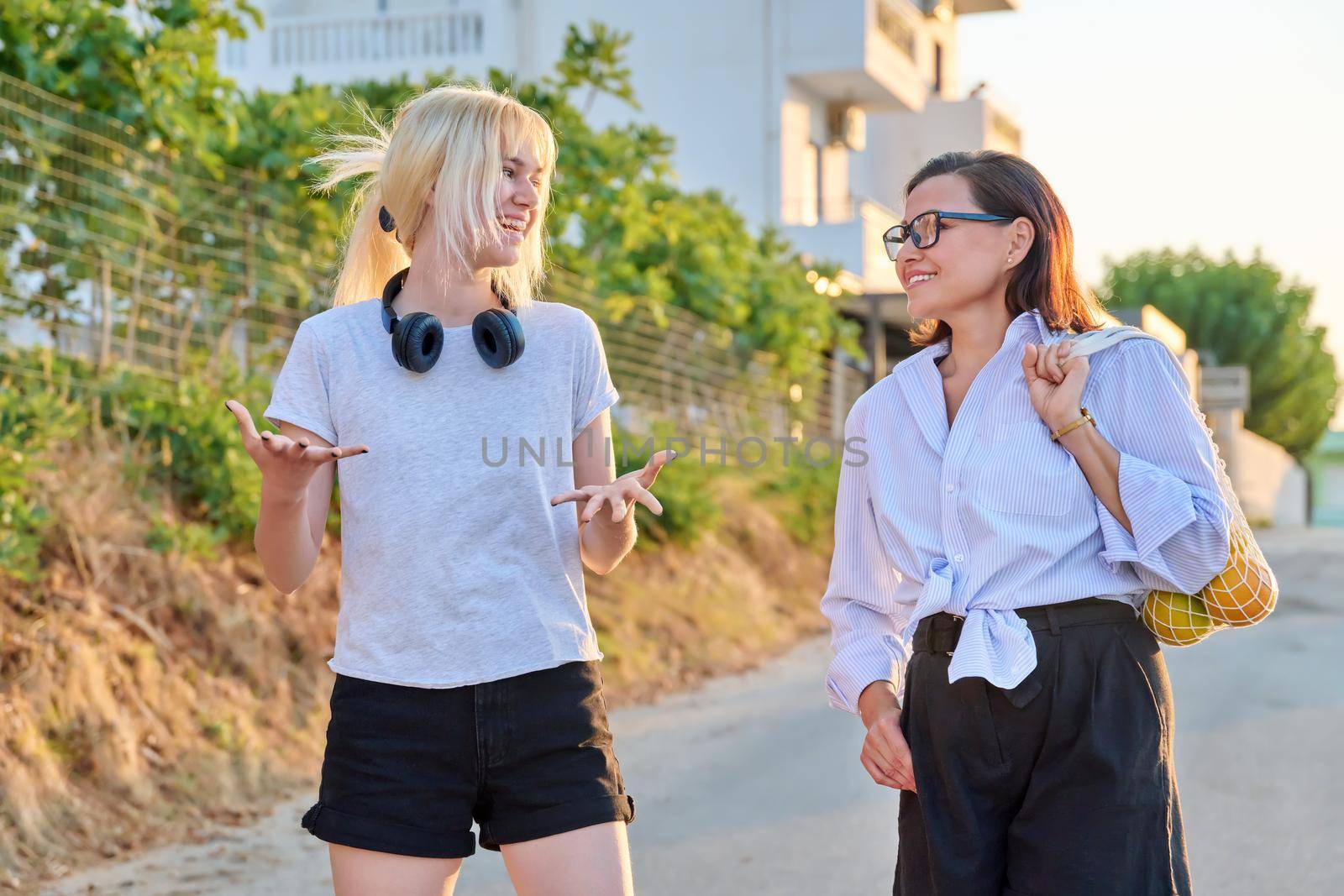 Summer walk of smiling mom and teenage daughter by VH-studio