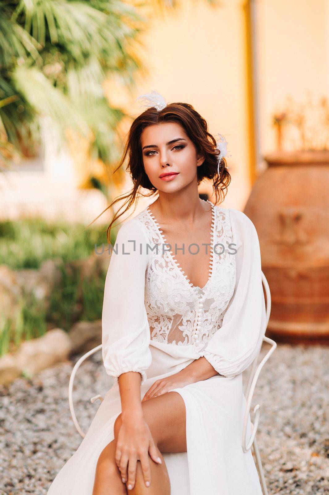 a beautiful bride is sitting on a chair and smiling in her underwear and dressing gown next to a Villa in Italy.morning of the bride in Tuscany by Lobachad
