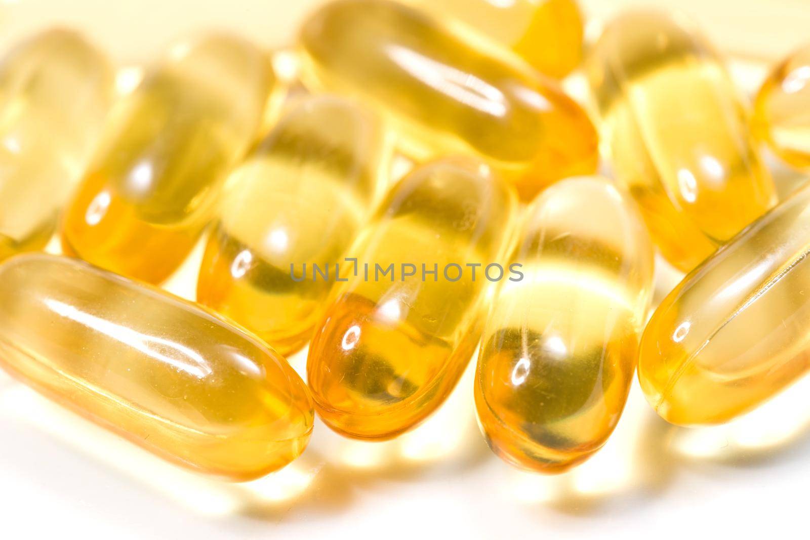 Close up golden color oil supplements in soft gel capsule, healthy product concept by whatwolf