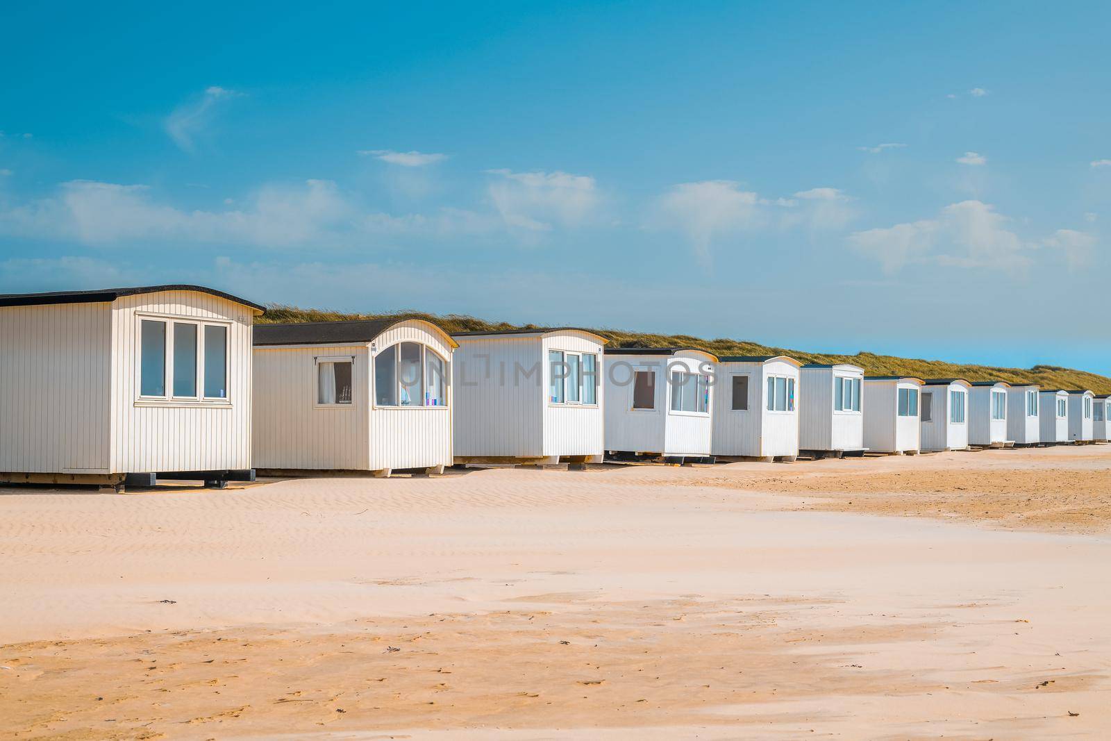 Little Muizenberg beach huts; beach huts on the sand with blue sky by isaiphoto