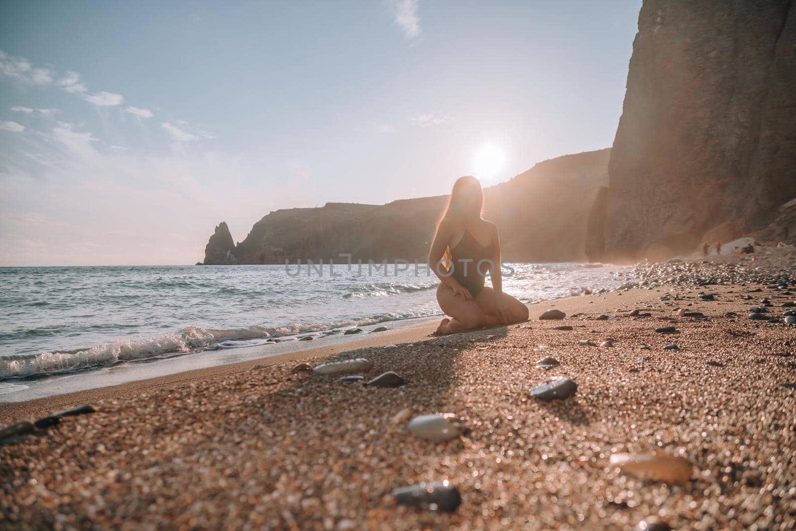 Selective focus. Happy carefree sensual woman with long hair in black swimwear posing at sunset beach. Silhouette of young beautiful playful positive woman outdoor. Summer vacation and trip concept by panophotograph