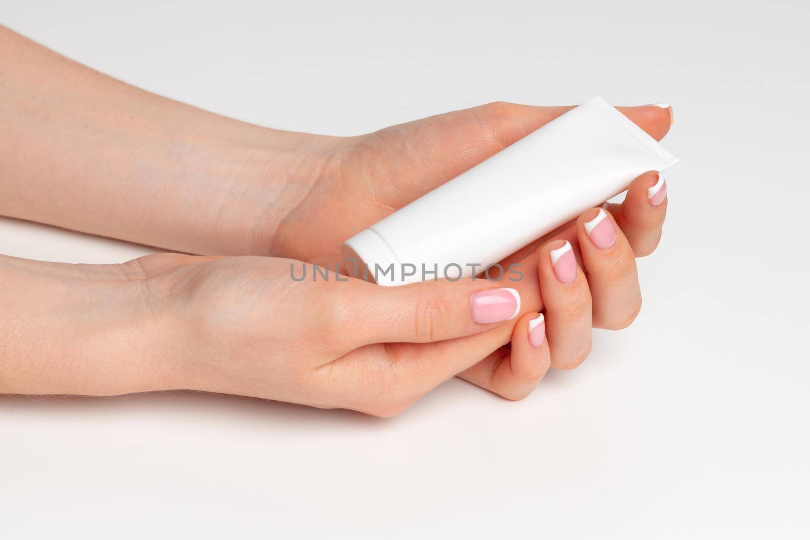 Female hand holding cosmetic bottle on white background