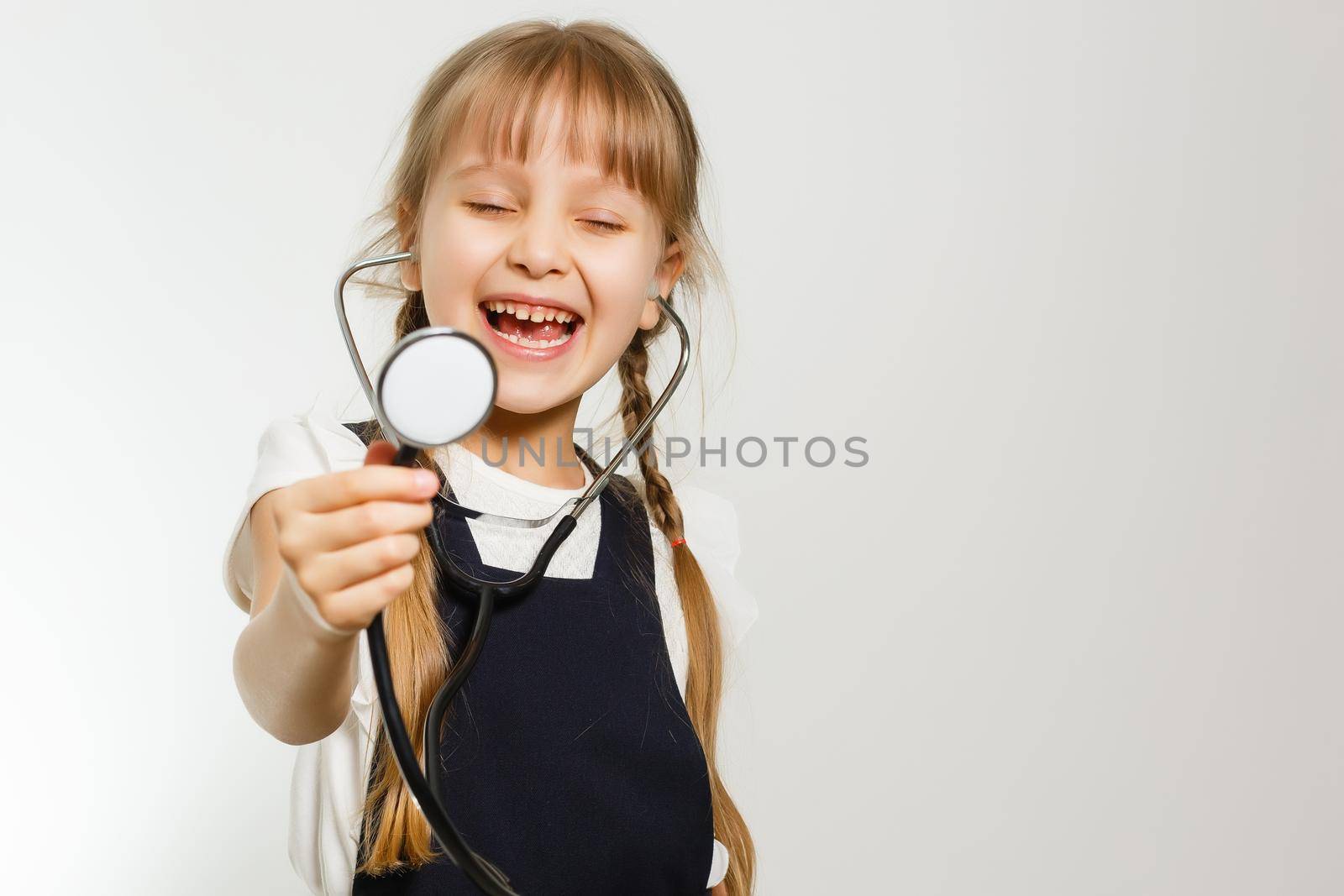 Smiling little girl playing doctor with stethoscope isolated on white by Andelov13