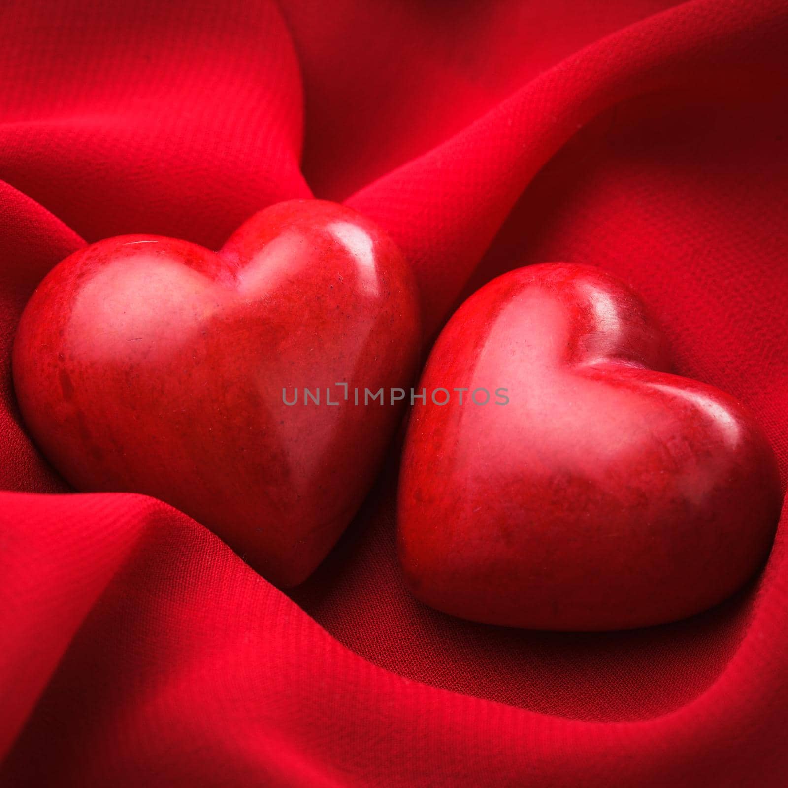 Two valentine hearts on red textile. Valentine's day concept