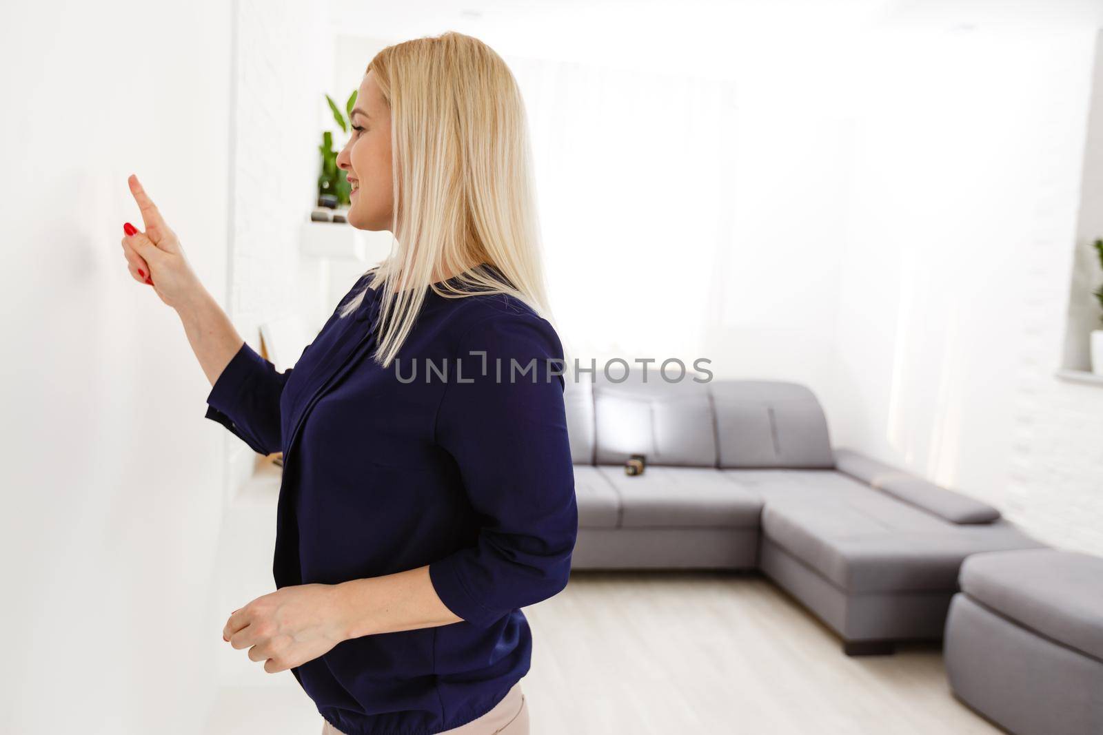 Middle aged woman pushing button of intercom by Andelov13
