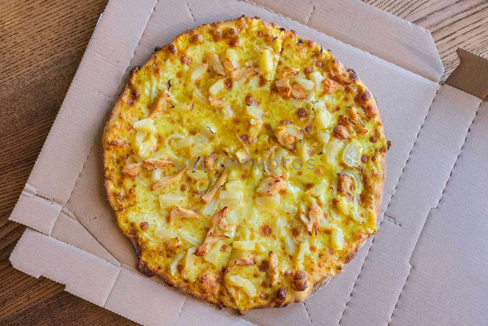Hot curry pizza in paper box close up. Top view. A delicious butter chicken curry pizza.