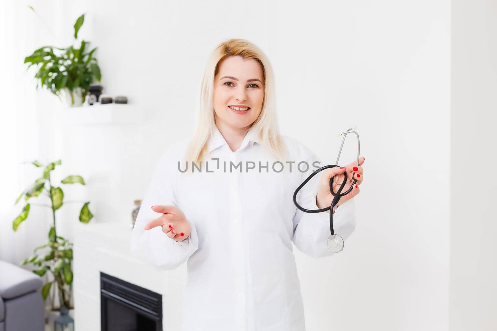 Smiling female doctor in white coat, on white