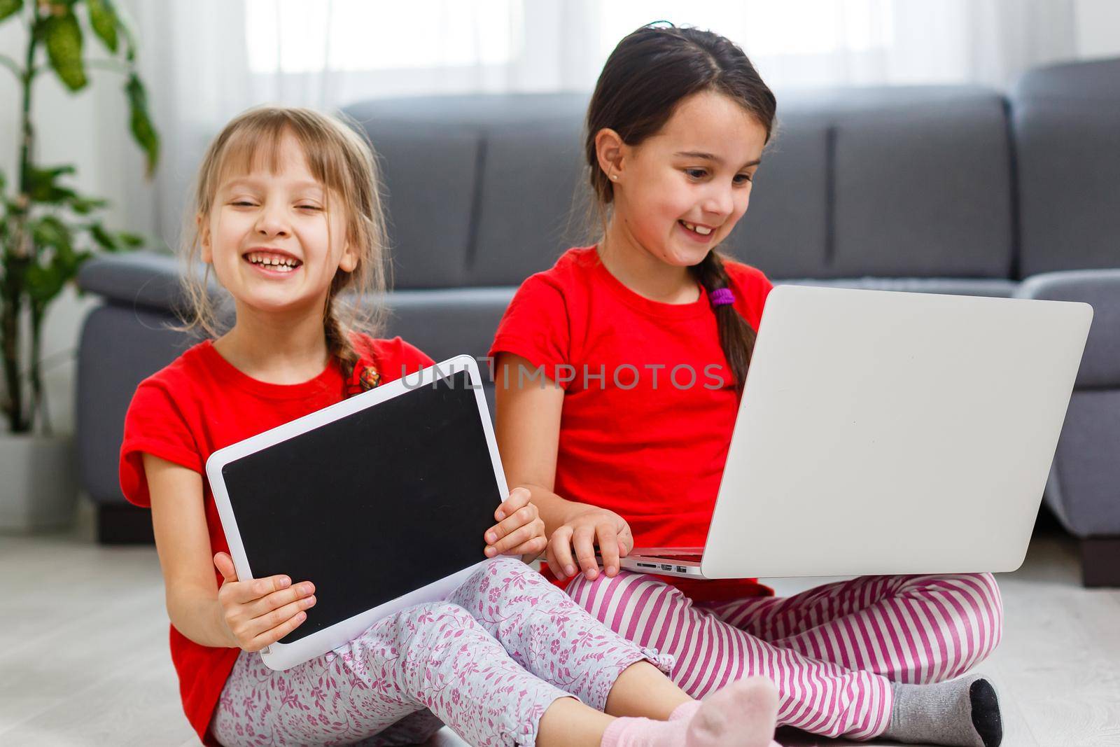 Two little girls sitting in front of a laptop and laughing, close-up, positive emotions, entertainment on the Internet for children by Andelov13