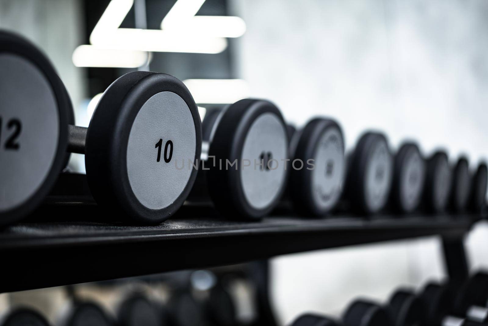 Close up photo of new dumbbells on a rack in a gym