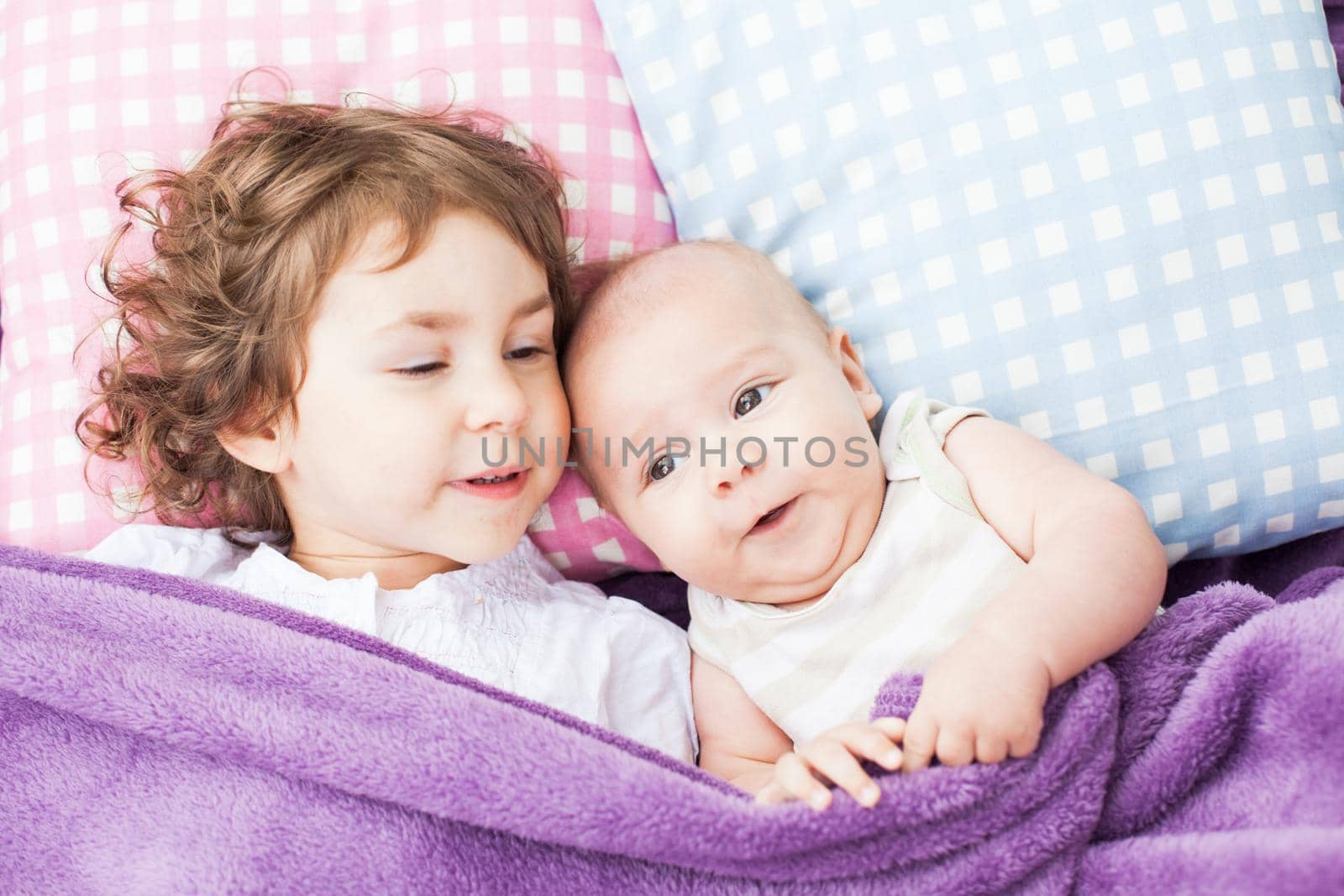 sister and brother play on the pillows