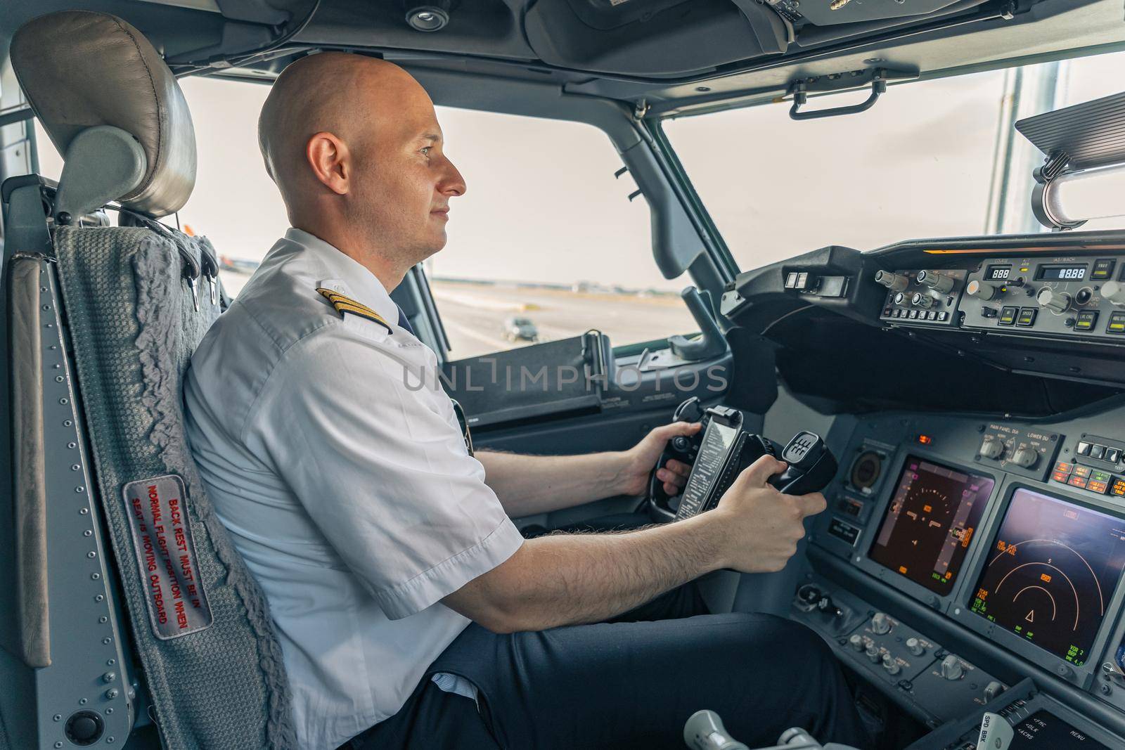 Confident pilot sitting in the cockpit and holding the steering wheel by Yaroslav_astakhov