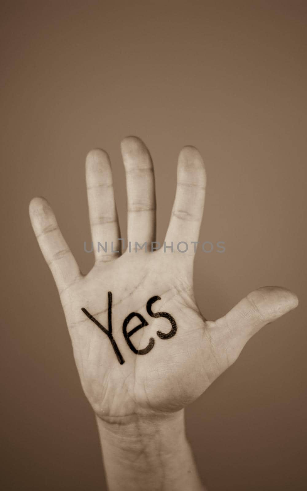 man showing the word "yes" written on the palm of a his hand