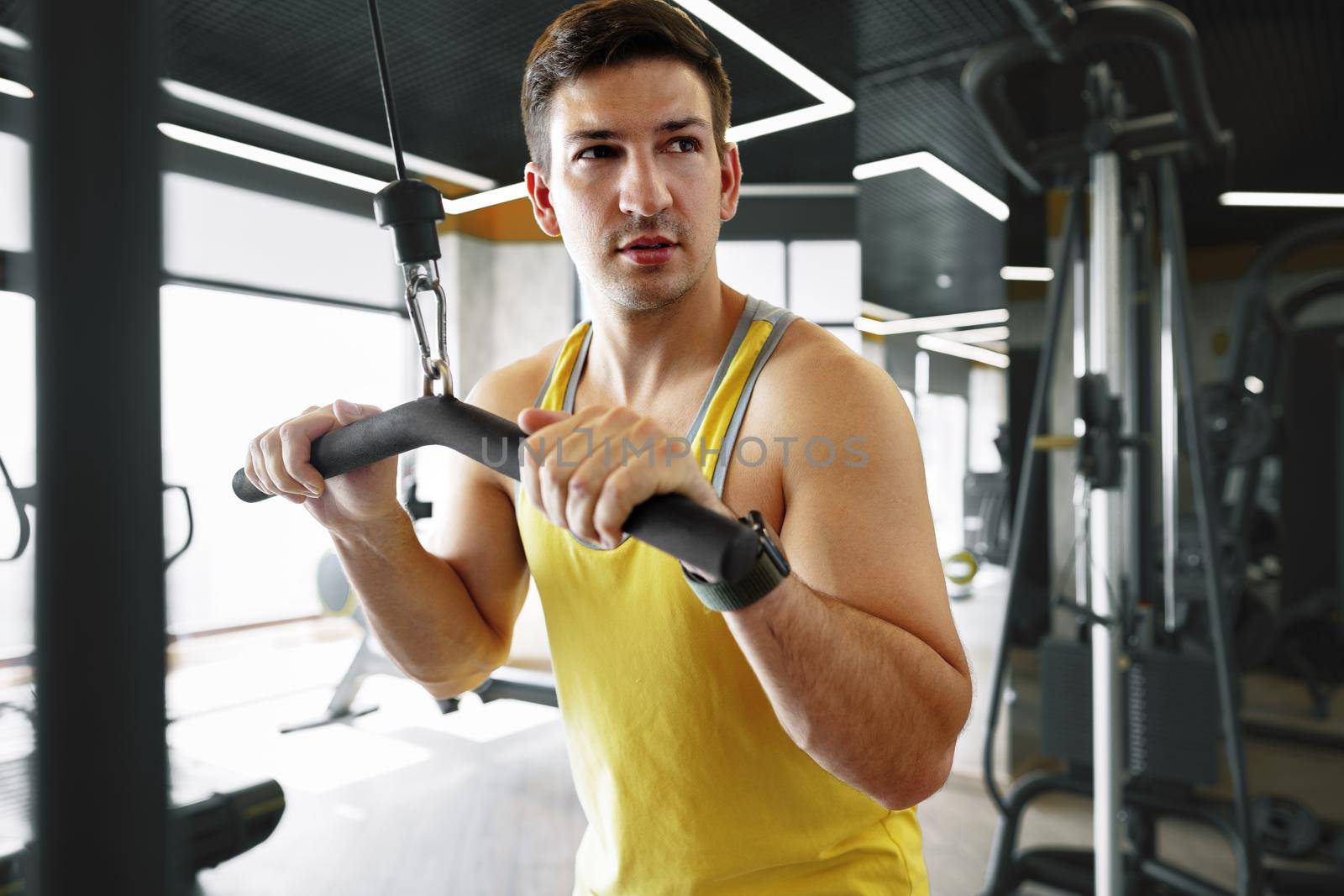 Young bodybuilder doing heavy weight exercise for biceps in a gym, close up