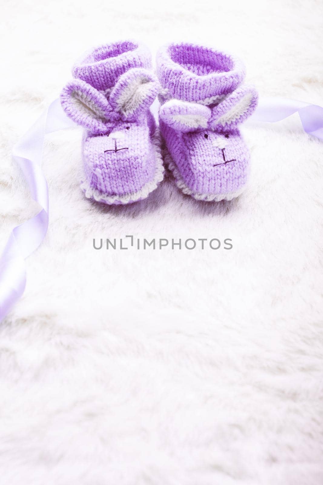 Knitted purple baby booties with rabbit muzzle over fur