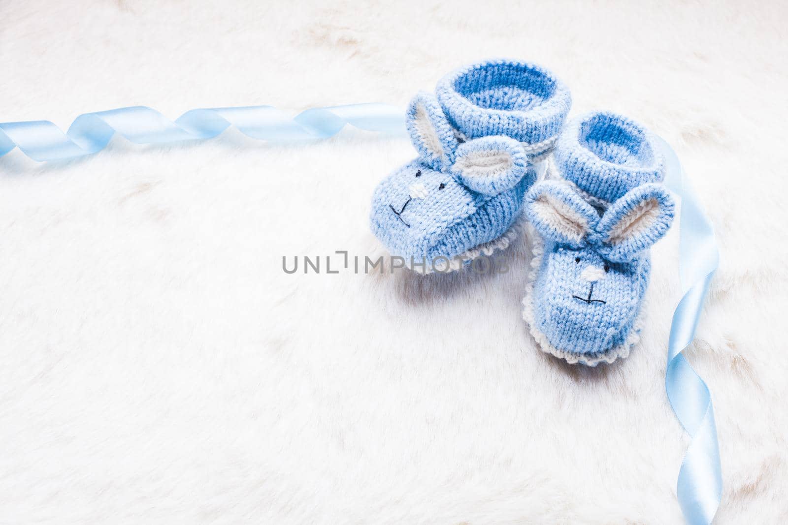 Knitted blue baby booties with rabbit muzzle for little boy