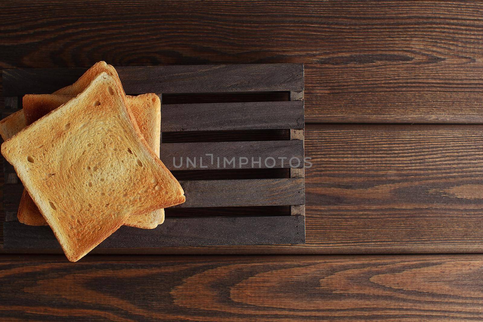 Several slices of toasted bread toasts on a wooden dark background.