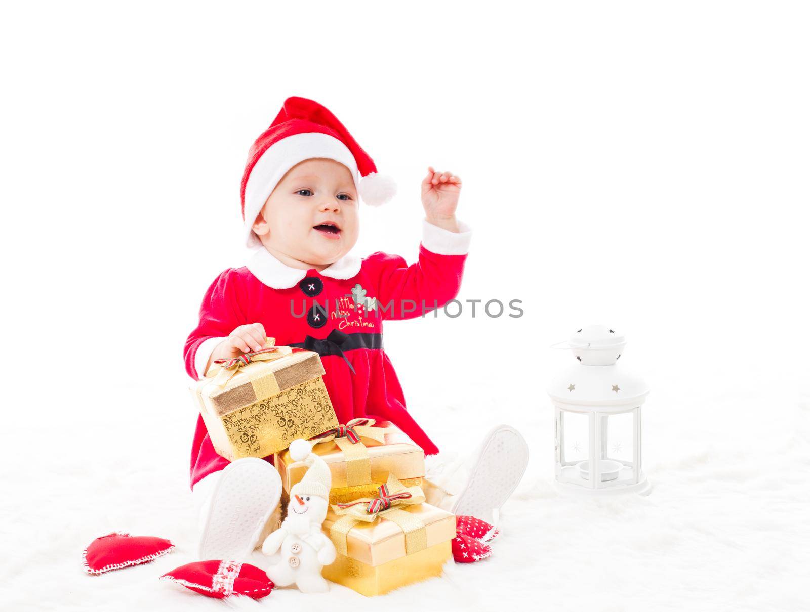Santa baby girl with gift box and christmas decorations on a fur
