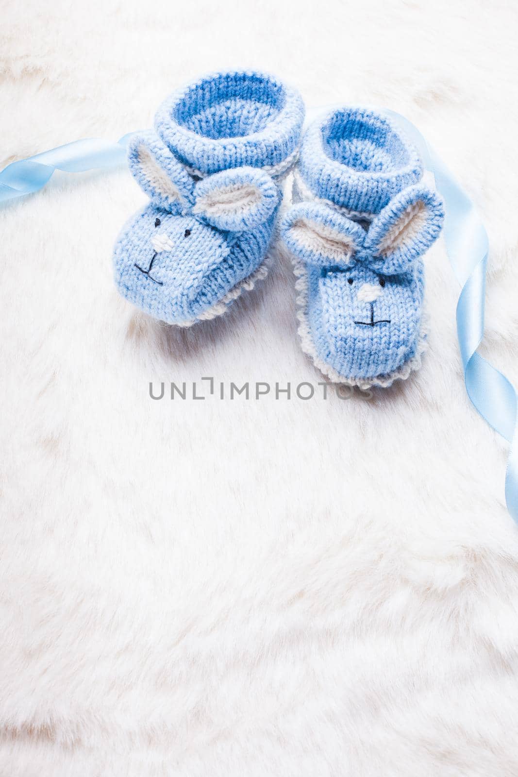 Knitted blue baby booties with rabbit muzzle for little boy