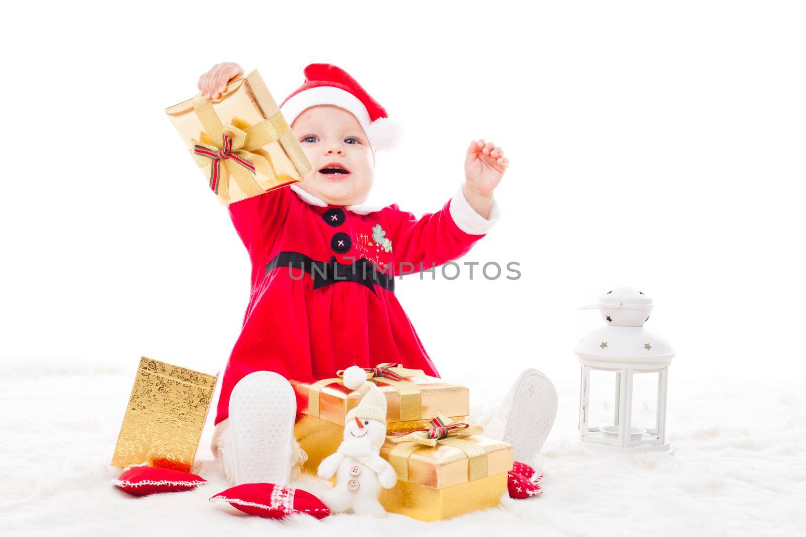 Santa baby girl with gift box and christmas decorations on a fur