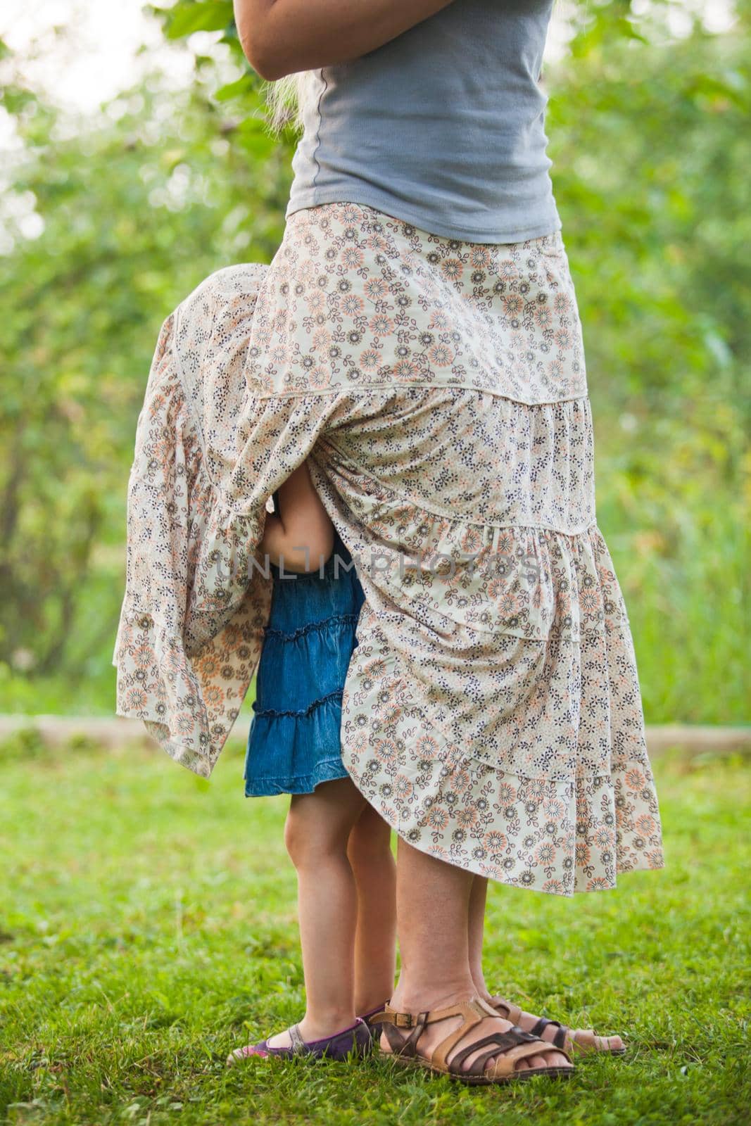 Little girl hids under a mother's skirt