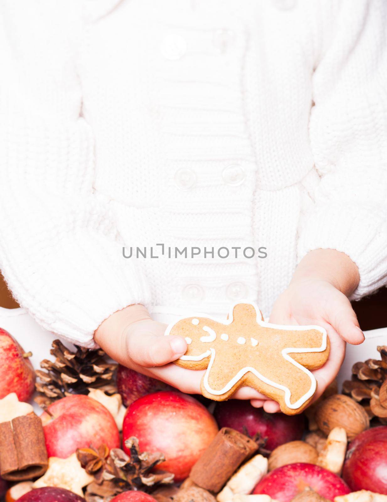 Child's hands hold a red apple and gingerman cookie