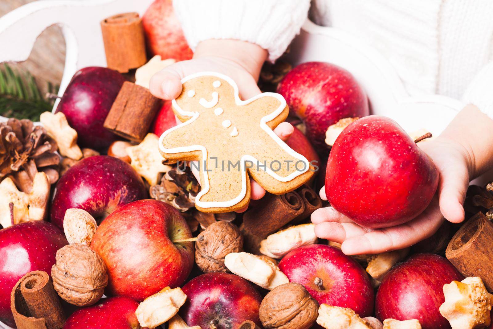 Child's hands hold a red apple and gingerman cookie