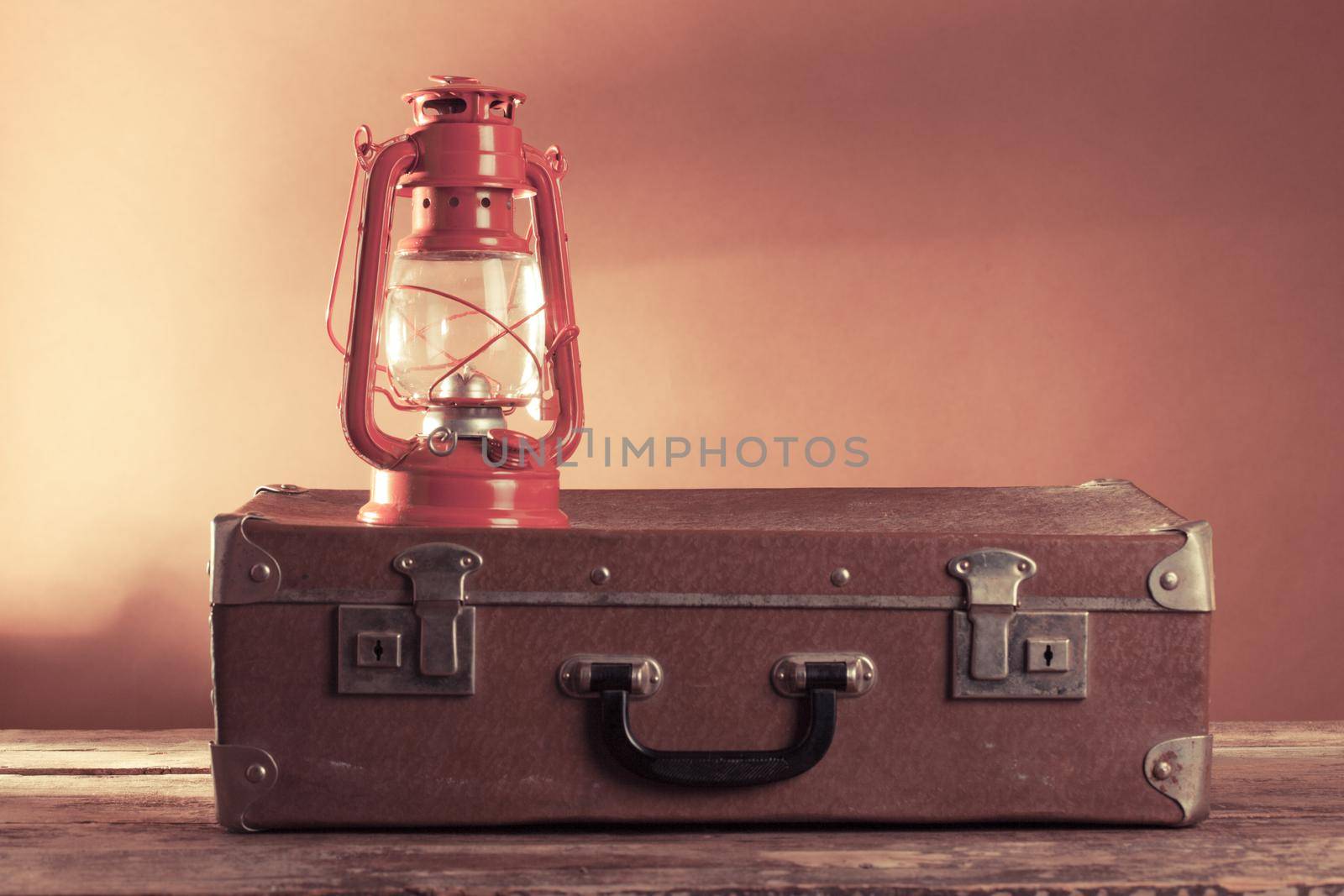 Old vintage suitcase and kerosene lamp on a woode floor