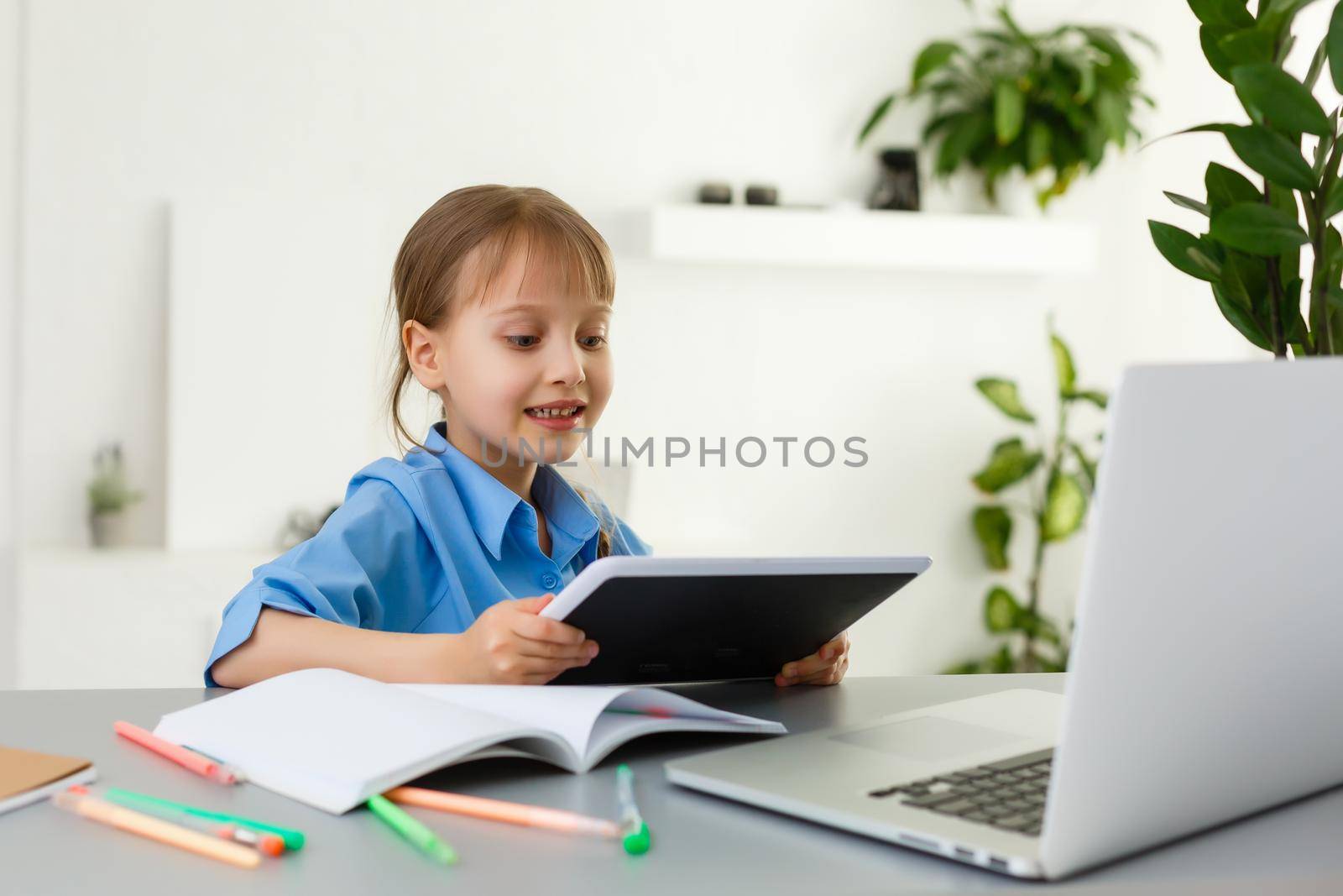 Remote lessons. The child smiles happily and gets knowledge remotely. Little girl study online learning from home. Online school. by Andelov13