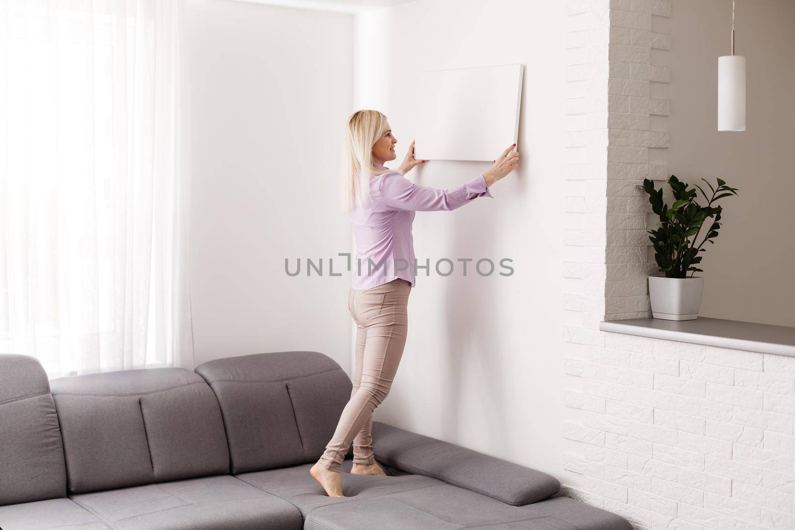 Happy european girl holding a blank canvas in her hands. Empty frame for text or photo. Young woman with mockup poster