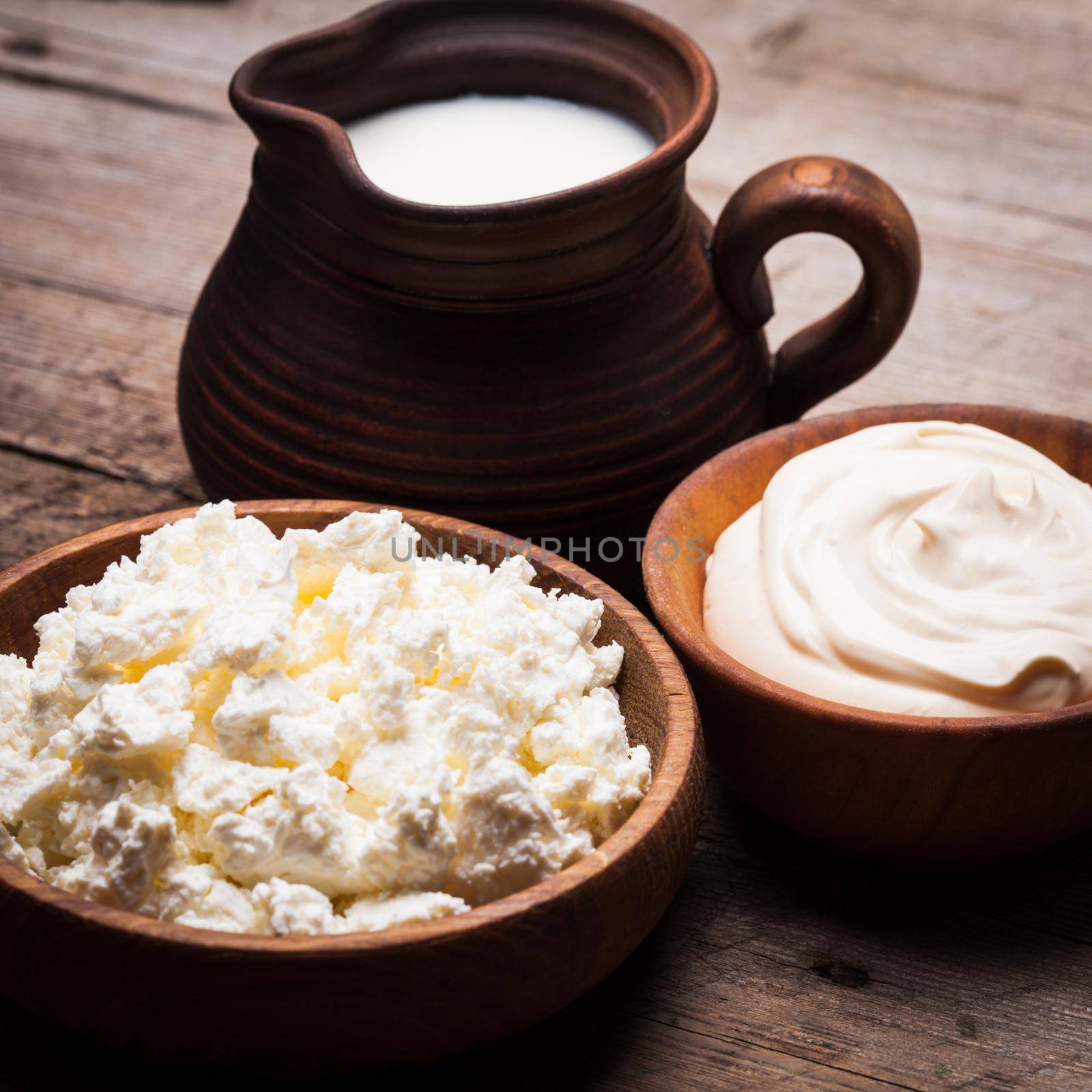 Milk, sour cream and curd on a wooden rustic board