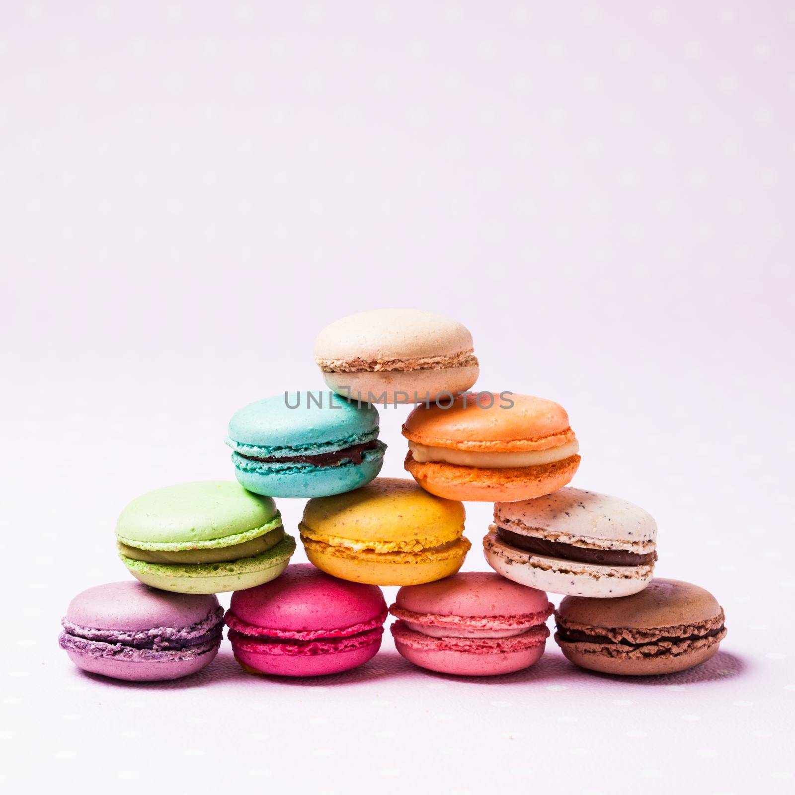 Colorful macaroons - french dessert over pink polka dot napkin