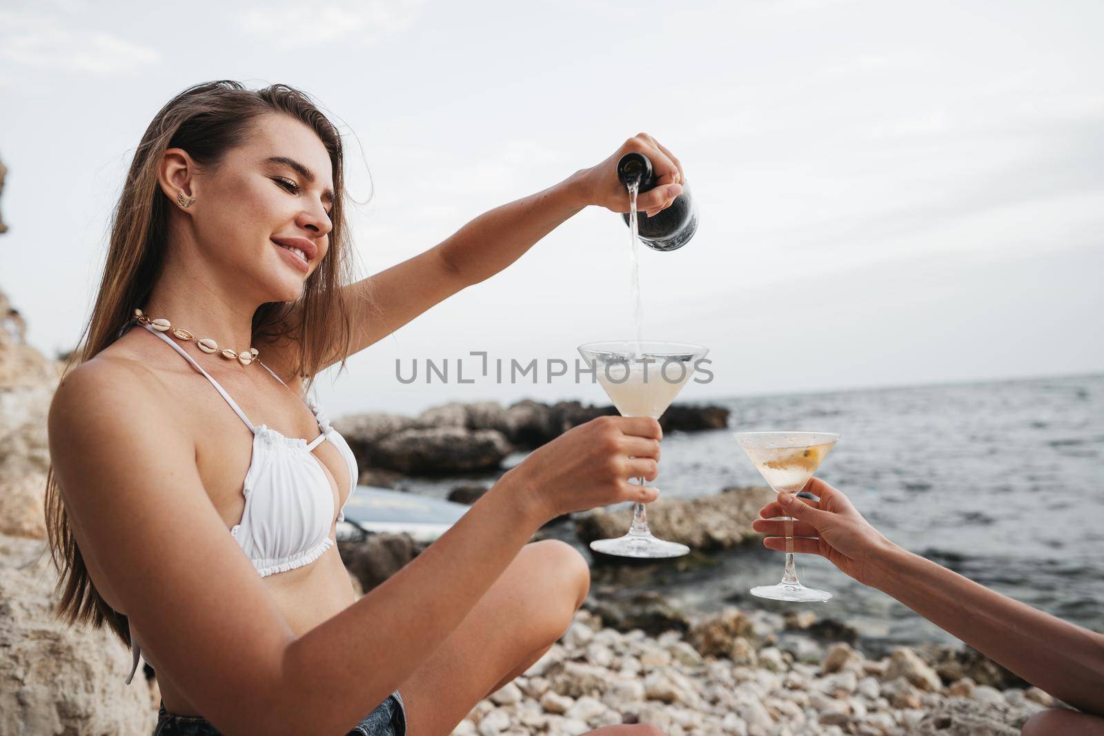 Portrait of young woman with cocktail glass chilling on a beach, close up