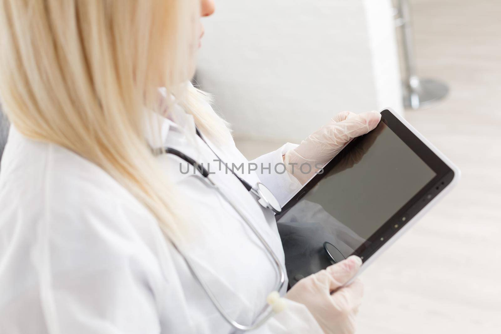 Female runette doctor using tablet, intelligent and lovely woman with the gadget and stethoscope in the white background by Andelov13