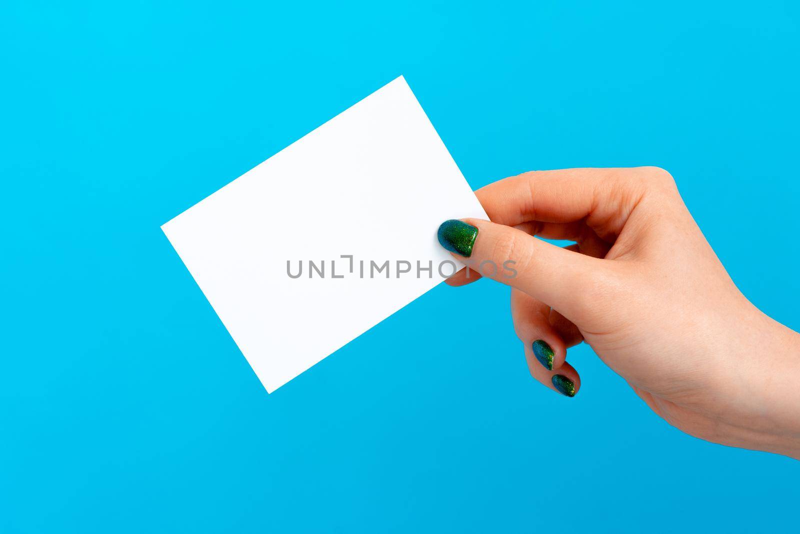 Woman hand holding blank card on blue background, close up.