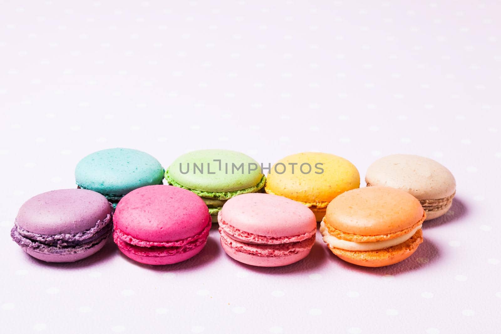 Colorful macaroons - french dessert over pink polka dot napkin